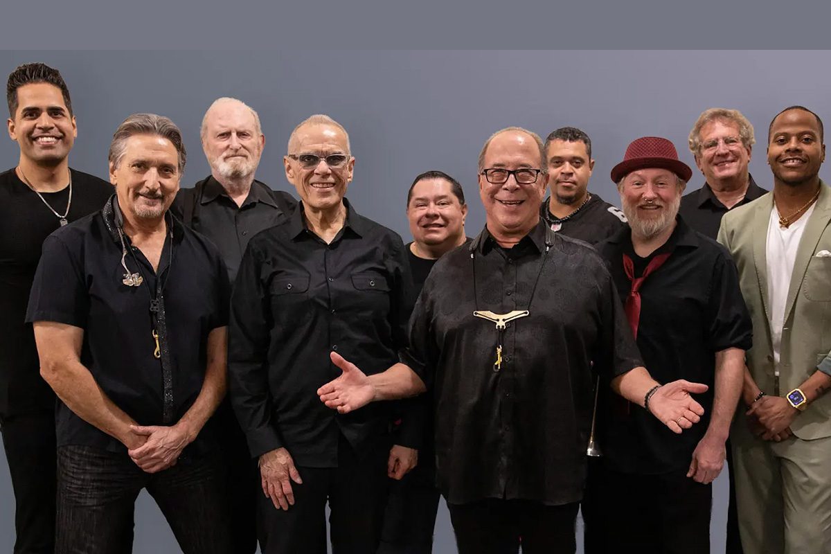 Tower of Power band members pose for a group photo, smiling and looking at the camera.