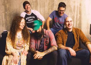 The Moonrise Cartel band members smiling together indoors.